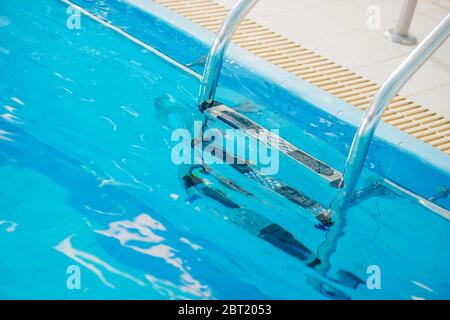 Primo piano della scala in acciaio Silver Stainelss immersa in acqua pulita della piscina. Foto Stock