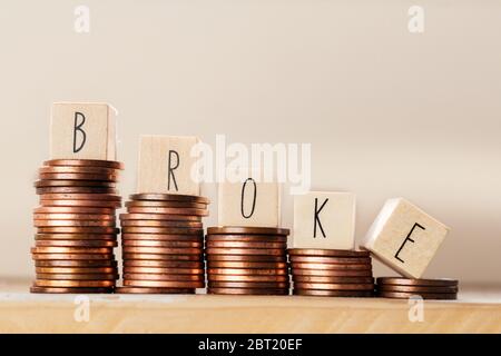 Cubi di legno con la parola rotto e mucchio di monete, soldi scalando le scale, concetto di base di affari Foto Stock