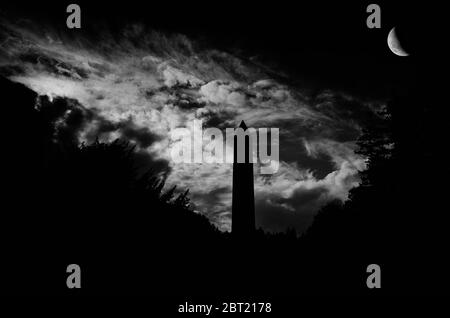 Torre rotonda del VI secolo, con le nuvole illuminate di luna, nell'insediamento monastico di Glendalough, nella contea di Wicklow, Irlanda Foto Stock