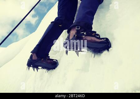 Primo piano di arrampicata su ghiaccio montagna in scarpe da montagna Foto Stock