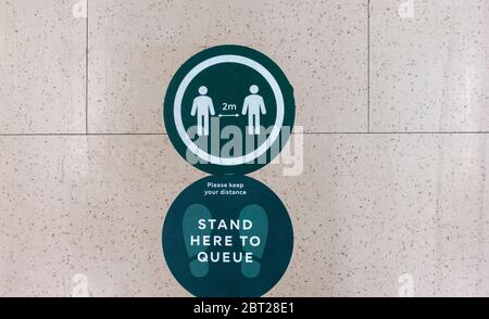 Marcatore di distanza sociale sul pavimento in un M&S Foodhall nel Regno Unito Foto Stock