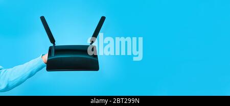 Nero router wifi a portata di mano su sfondo blu Foto Stock