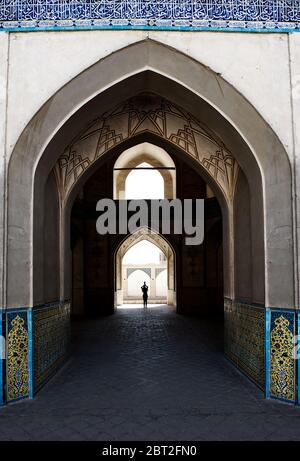 Donna in piedi nel mezzo della vecchia moschea, Isfahan, Iran Foto Stock