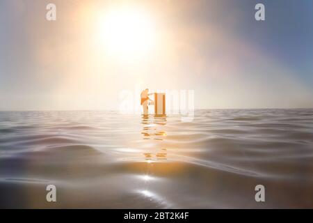 Uomo d'affari in piedi nell'oceano cercando attraverso un armadietto di deposito Foto Stock