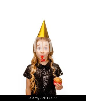 ragazza in un cappello di festa in un abito nero di paillettes che tiene una cupcake di compleanno Foto Stock