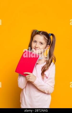 ragazza con due code che tengono un notebook Foto Stock