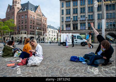 Un attivista ha visto cucire usato vestiti mentre sedeva sul suo skateboard.Extinction Rebellion Nederland ha organizzato un'azione di moda XR, per mostrare un'alternativa alla frenetica industria della moda veloce. Circa venti attivisti si sono esibiti in piazza Dam, nel centro di Amsterdam, per cucire e riparare i vestiti usati, per sostenere le piccole etichette di moda sostenibili che stanno attraversando un momento difficile, e due volte pensando prima di acquistare nuovi vestiti. Durante l'azione, e secondo le regole di Coronavirus, gli attivisti hanno mantenuto la distanza sociale. Foto Stock