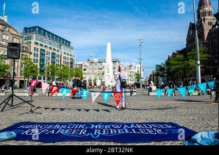 Un attivista del clima ha tenuto un discorso al centro della piazza.l'estinzione Rebellion Nederland ha organizzato un'azione di moda XR, per mostrare un'alternativa alla frenetica industria della moda. Circa venti attivisti si sono esibiti in piazza Dam, nel centro di Amsterdam, per cucire e riparare i vestiti usati, per sostenere le piccole etichette di moda sostenibili che stanno attraversando un momento difficile, e due volte pensando prima di acquistare nuovi vestiti. Durante l'azione, e secondo le regole di Coronavirus, gli attivisti hanno mantenuto la distanza sociale. Foto Stock