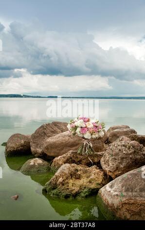 bouquet di rose bianche e viola su pietre Foto Stock