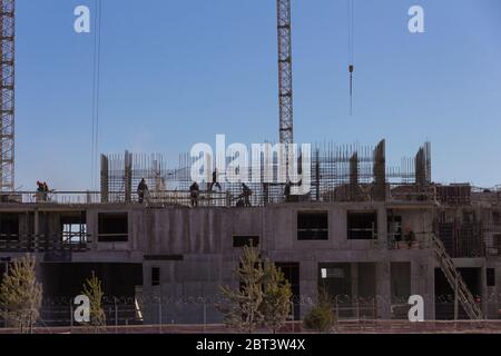 Lavoratori industriali e costruttori con elmetto in uniforme versare calcestruzzo e montare la carcassa di rinforzo in cantiere Foto Stock