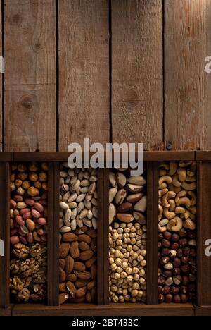 Nocciole, pistacchio, noci, ceci arrostiti, arachidi e molto altro in una scatola di legno su un tavolo di legno con posto per il logo Foto Stock