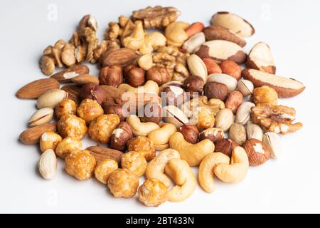 Nocciole arrostite al caramello, nocciole, pistacchi, anacardi, noci e arachidi su fondo bianco Foto Stock