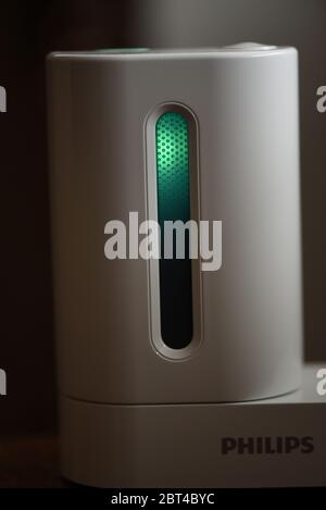 Vista esterna dello spazzolino Philips Sonicare con igienizzatore UV in azione con sportello chiuso e luce ultravioletta accesa. L'azienda rivendica la tecnologia hel Foto Stock