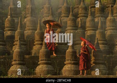 Due monaci novizi che camminano tra gli stupidi, Bagan, Mandalay, Myanmar Foto Stock