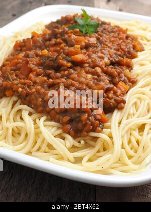 Saporiti spaghetti organico vegetariano con il ragù alla bolognese in un rustico tavolo da cucina Foto Stock