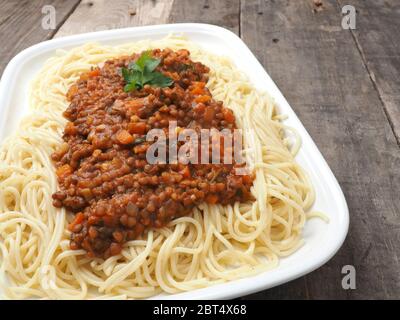 Saporiti spaghetti organico vegetariano con il ragù alla bolognese in un rustico tavolo da cucina Foto Stock