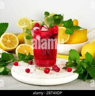 Dissetante bevanda estiva di fragole e mirtilli rossi su un bianco tavola di legno, dietro di esso sono il giallo dei limoni e il verde di foglie di menta Foto Stock