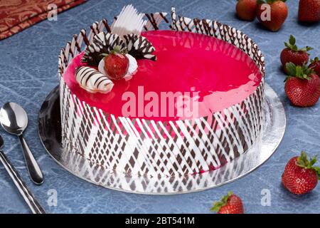 Torta al formaggio con fragole con cioccolato bianco grattugiato, panna montata e fragola glassata come guarnizione Foto Stock