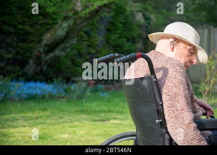 Sul suo patio giardino posteriore in un caldo pomeriggio di primavera inglese, il recupero da lesioni alla testa, danni al cervello e la gestione della demenza. Foto Stock