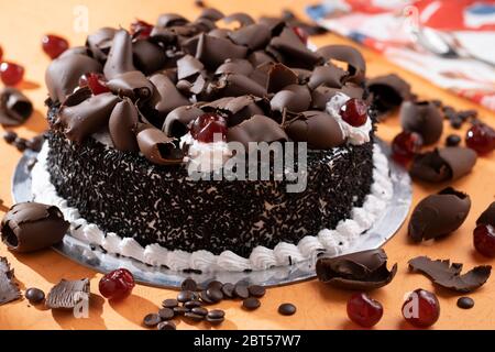 Torta della foresta nera con guarnizioni di cioccolato grattugiato, ciliegia glassata su panna montata Foto Stock