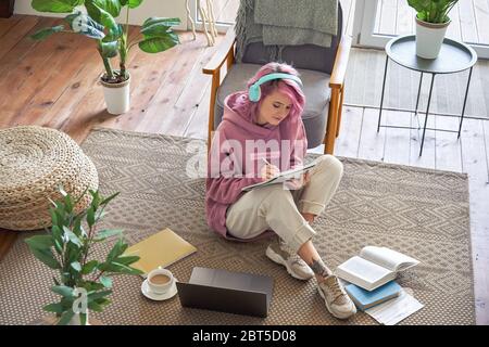 Teen girl indossa cuffie videoconferenza su computer portatile sedersi a terra, vista dall'alto. Foto Stock