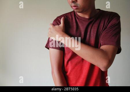 Primo piano di un giovane che soffre di dolore alla spalla Foto Stock