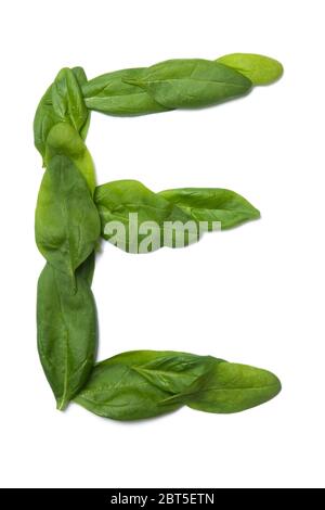 Lettera e dell'alfabeto inglese di foglie di spinaci verdi fresche su sfondo bianco isolato. Naturale motivo bonatico a base di foglie. B Foto Stock