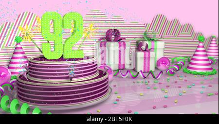 Torta di compleanno viola rotonda 2 decorata con scintille colorate e linee rosa su un tavolo luminoso con ruscelli verdi, cappelli da festa e scatole regalo con rosa Foto Stock