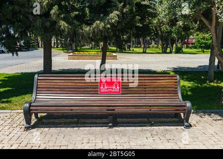 Baku, Azerbaigian, tenere la distanza, poster su una panchina del parco Foto Stock