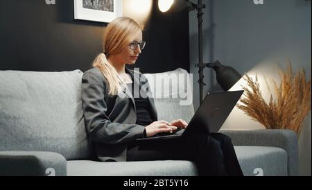 Donna d'affari che lavora con un computer portatile sul divano Foto Stock