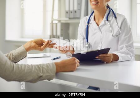 Medico senza volto dà al paziente una prescrizione medica. Paziente e medico in ufficio di una clinica medica.Medicina clinica ospedale. Foto Stock