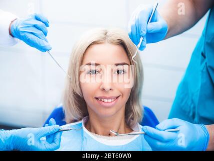 Dentisti esaminano la ragazza sorridente bionda Foto Stock