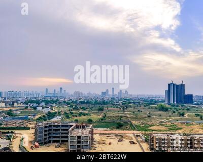 Paesaggio aereo che mostra il paesaggio di gurgaon con luce solare crepuscolo e nuvole, incompiuto sotto edifici di costruzione e grattacieli in lontananza Foto Stock