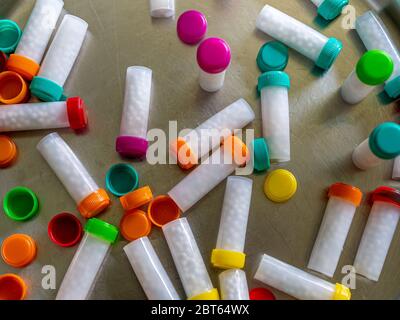 Bottiglie colorate in plastica riempite con pillole/globuli omeopatici bianchi Foto Stock