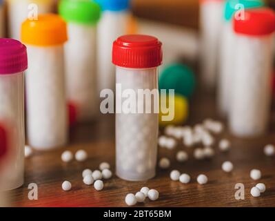 Bottiglie colorate in plastica riempite con pillole/globuli omeopatici bianchi Foto Stock