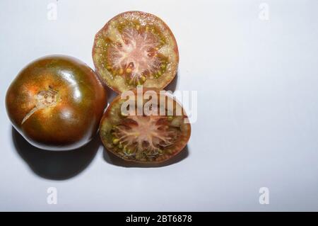 Foto aerea di un gruppo di due pomodori Kumato uno di loro mezzo aperto su sfondo bianco Foto Stock