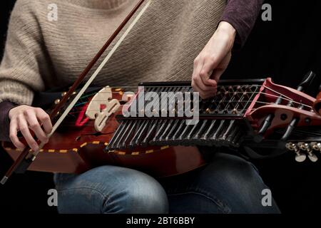 Musicista femminile che sintonizza la sua moderna ricostruzione di una nyckelharpa svedese medievale prima di una performance in primo piano sui tasti dello strumento e la tangente Foto Stock