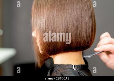 Vista posteriore della mano del parrucchiere pettinatura capelli corti di donna in parrucchiere. Foto Stock