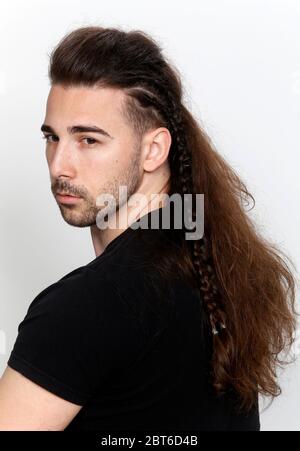 Modello maschile elegante con trecce in posa in studio su sfondo isolato. Stile, acconciatura, concetto di moda. Foto Stock