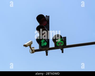 Semaforo verde con conteggio alla rovescia digitale e sorveglianza con telecamere di sicurezza del traffico (TVCC) contro il cielo blu. Moderno controllo automatico del traffico. Foto Stock