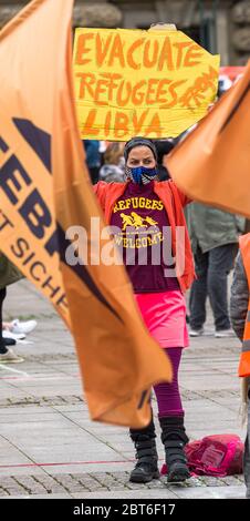 Amburgo, Germania. 23 maggio 2020. Un attivista dell'organizzazione di soccorso dei rifugiati Seebrücke sta dimostrando con un segnale che recita "evacuare i rifugiati dalla Libia" nel mercato comunale per un programma nazionale di accoglienza dei rifugiati che attualmente si trovano nei campi al confine esterno dell'UE. Secondo la polizia di Amburgo, sabato a Rathausmarkt sono emminate 300 persone per l'evacuazione dei campi profughi in Grecia e l'accoglienza di almeno 1000 rifugiati nella città anseatica. Credit: Markus Scholz/dpa/Alamy Live News Foto Stock