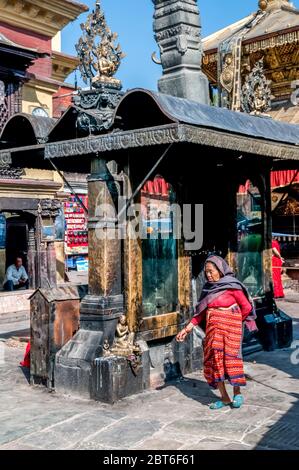 Kathmandu. Scena generale con una signora adoratrice che cammina intorno al tempio stupa al tempio buddista di Swayambhunath Foto Stock