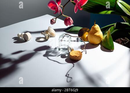 Vita morta di vari oggetti, texture e piante. La composizione è di pera, orchidea, spugna, vetro, rametto, pietra, specchio e altri materiali. Foto Stock