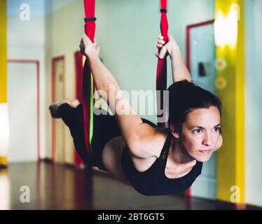 Giovane donna che esegue acrobazie yoga in aria su un'altalena. Concetto di acrobazie yoga Foto Stock