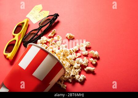 Tazza di carta con popcorn su sfondo rosso. Punti e biglietti per il cinema Foto Stock