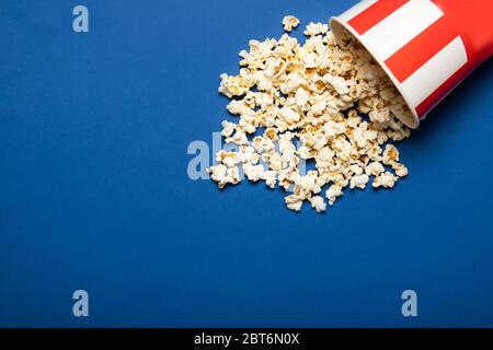 Tazza di carta con popcorn su sfondo blu Foto Stock