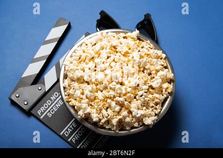 Piatto con popcorn e clapper di film su sfondo blu Foto Stock