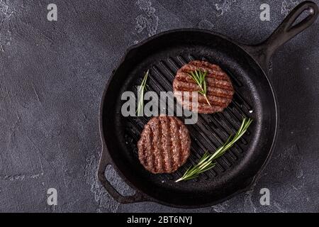 Cotoletta fritta per hamburger con spezie sulla padella alla griglia, vista dall'alto, spazio per la copia. Foto Stock