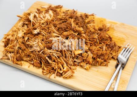 Maiale tirato homecoked servito sminuzzato su un asse di legno. Il piatto è stato preparato in un piano cottura lento e cotto per nove ore. Foto Stock