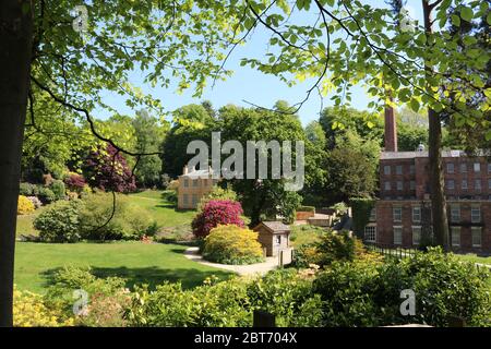 Vista della National Trust Quarry Bank House e mulino e giardini in primavera incorniciati da alberi Foto Stock